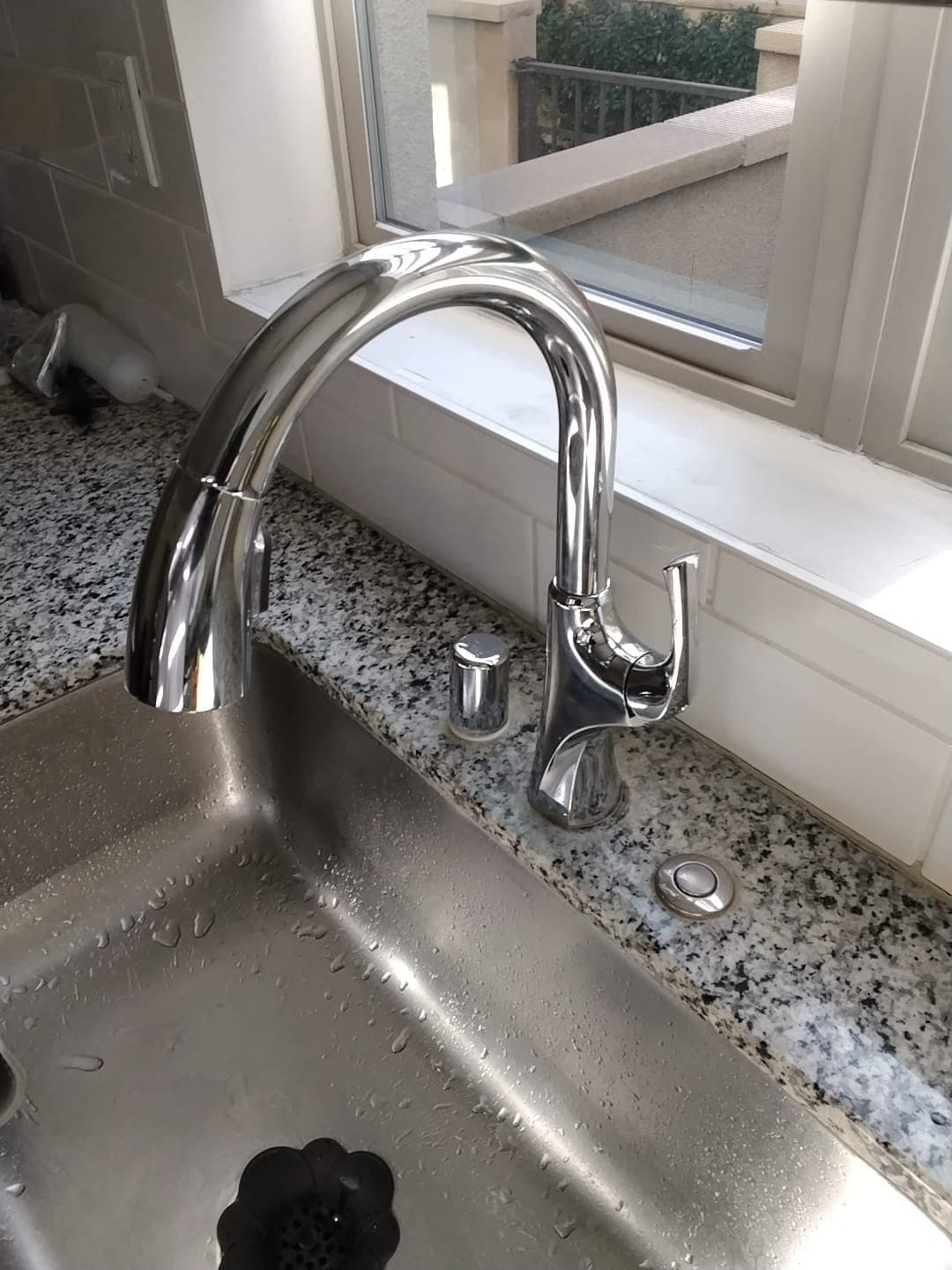 New chrome pull-down kitchen faucet installed on a granite countertop