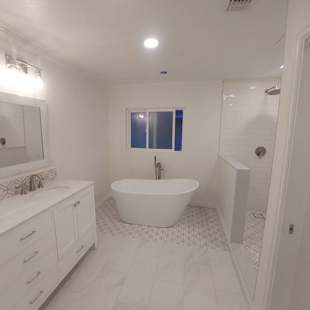 Modern bathroom remodel featuring a freestanding white bathtub, sleek cabinetry, and contemporary shower area with tile flooring and natural lighting.